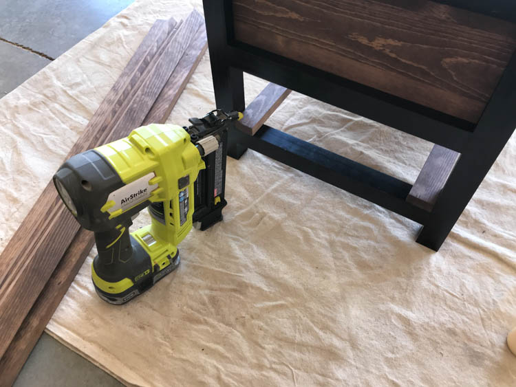 Installing lower shelf slats with a brad nailer on a DIY storage bench