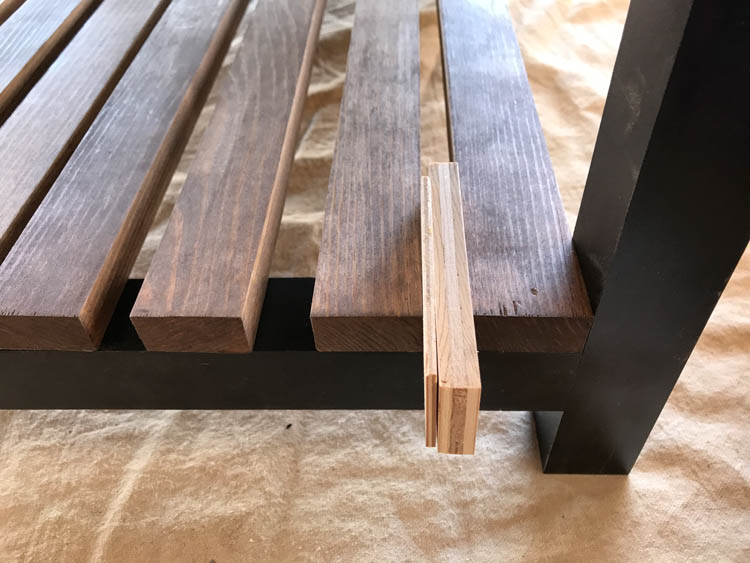 Wood spacer used to evenly space lower shelf slats on DIY storage bench