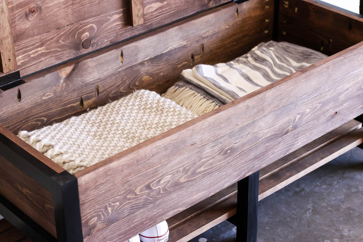 Interior storage compartment of DIY wooden bench filled with blankets