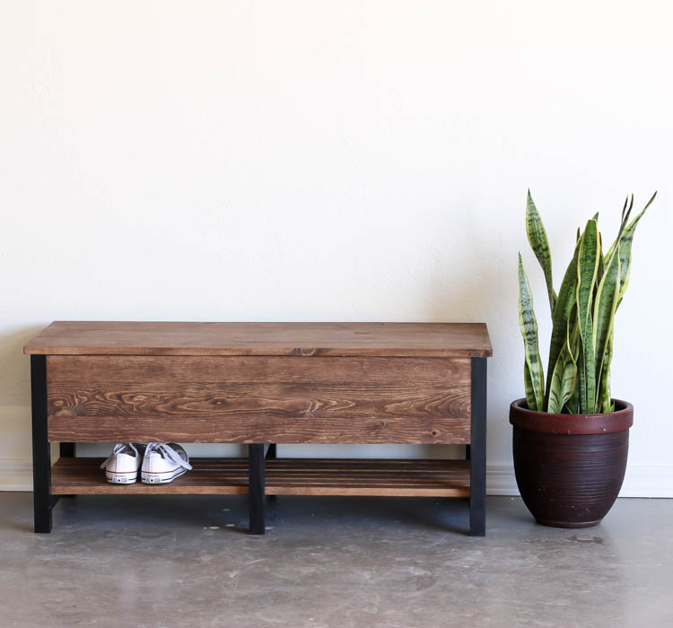 Finished wooden storage bench beside snake plant in entryway