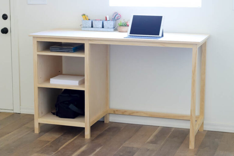 DIY counter-height desk with open shelving built from pine wood, styled with office supplies and a tablet