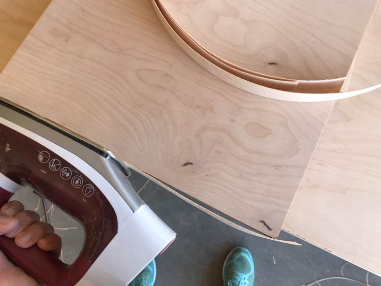 Iron being used to apply iron-on veneer edge banding to the edge of a plywood panel for a DIY modern coffee table