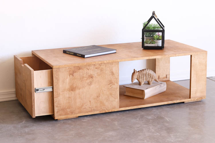 Three-quarter view of a finished DIY modern coffee table with the hidden side drawer pulled open, revealing the drawer box and metal slide hardware