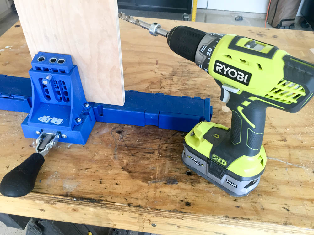 Kreg Jig clamped to a plywood piece with a RYOBI drill positioned to drill pocket holes for a DIY kids activity table