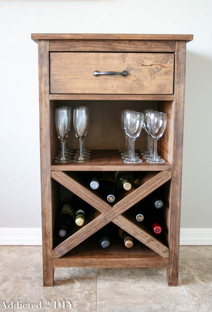 Front view of a finished DIY wine cabinet with X-style wine rack, glass storage shelf, and single drawer, stained in warm walnut brown