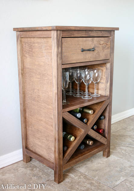 Side angle view of finished DIY wood wine cabinet showing plywood side panel, X wine rack, glass shelf, and drawer