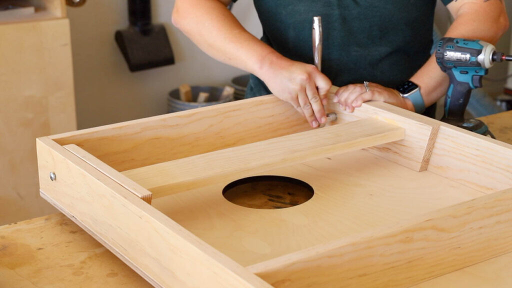 Installing a carriage bolt through the cornhole board frame side to attach the folding leg