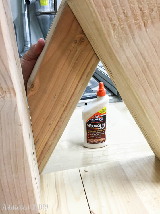 Close-up of angled bottom shelf boards being held in place with Elmer's Carpenter's Wood Glue Max during assembly of the DIY outdoor console table