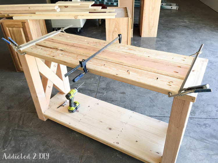 2x6 and 2x8 tabletop planks clamped together with bar clamps during assembly on top of the console table base in the workshop