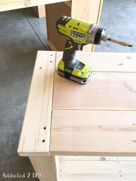 Ryobi impact driver driving screws through pre-drilled pocket holes in the breadboard end of the DIY outdoor console table tabletop