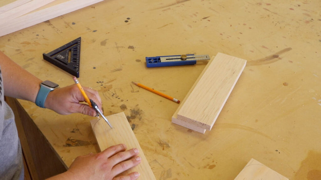 Marking the pivot radius on cornhole board legs using a compass and multi-mark tool on a workbench