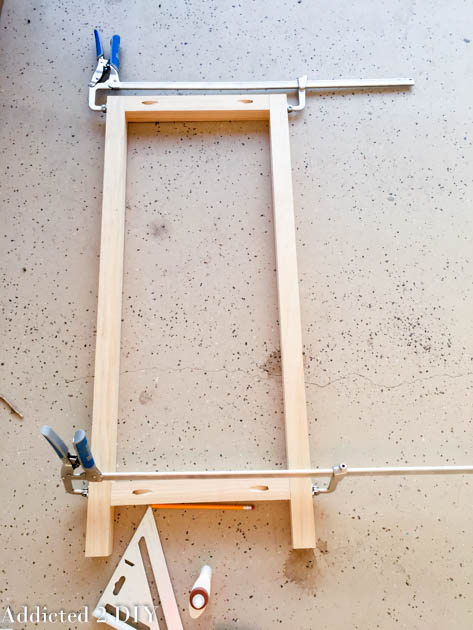 2x2 pine cabinet side frame clamped flat on garage floor with pocket holes visible on rails