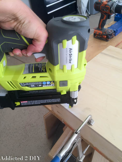 Ryobi AirStrike 18-gauge brad nailer being used to attach trim pieces to the DIY wine cabinet