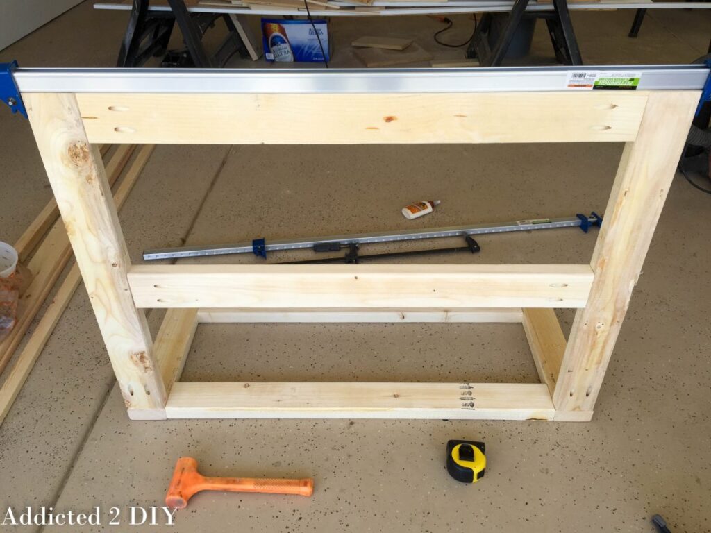 Assembled back frame of a DIY wooden bike rack showing two upright posts and two horizontal cross supports, held together with pocket screws