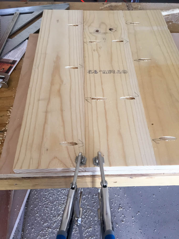 Close-up of pocket holes in pine boards with pencil arrows indicating correct drilling direction for DIY nightstand