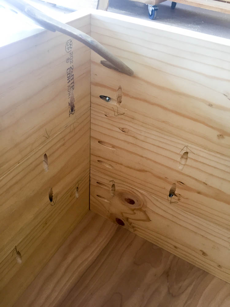 Interior corner of DIY nightstand case showing pocket screws joining pine side panels together