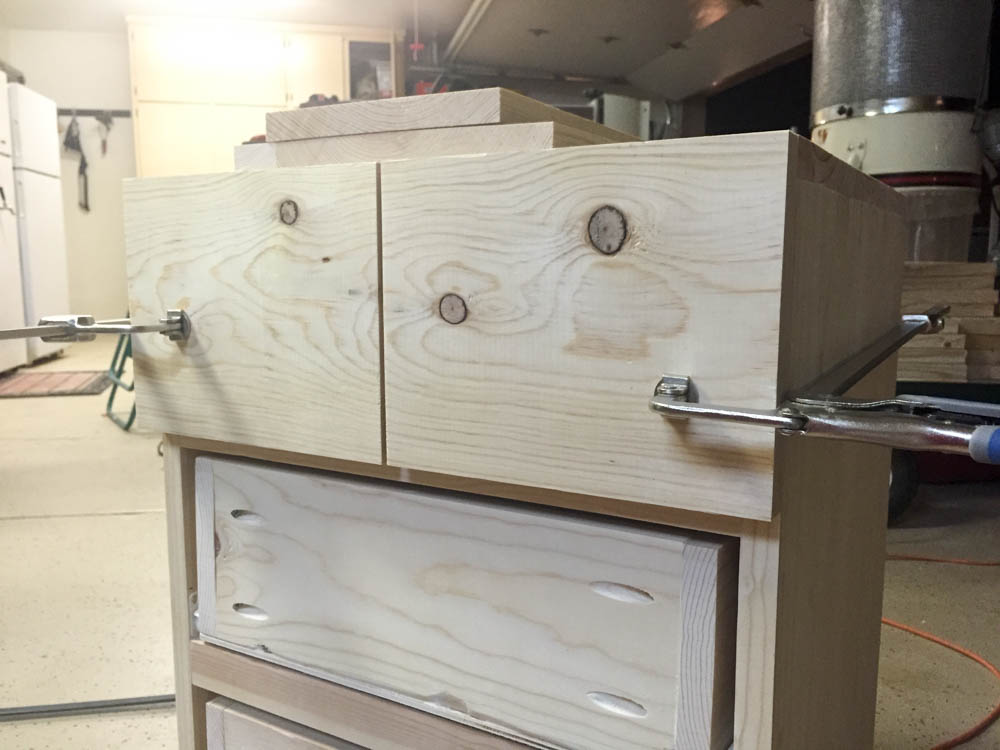 Top drawer face clamped in position on DIY nightstand showing false double-drawer front design held with Kreg clamps before nailing