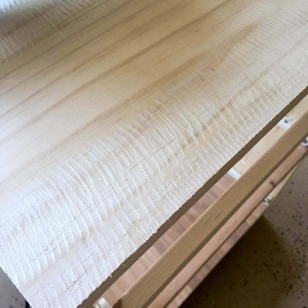 Close-up of deep parallel grinder marks across pine board edge showing the faux sawmill texture effect before sanding