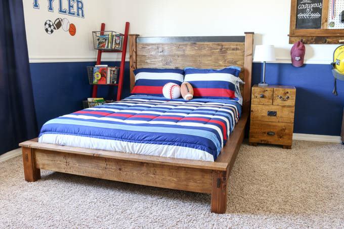 Finished DIY rustic double bed with dark wood headboard and metal cap detail in a boys bedroom with navy and white striped bedding
