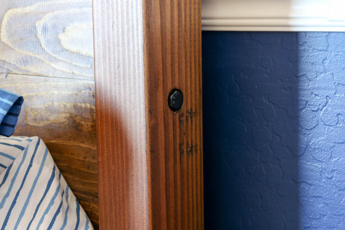 Close-up of a lag bolt inset into the side of a stained 4x4 headboard leg on a DIY PB Teen Emerson knockoff bed