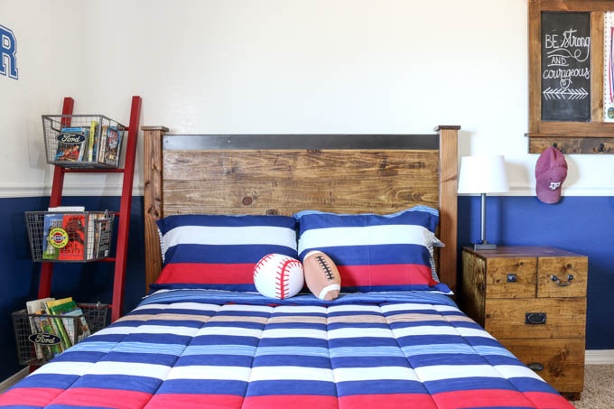 Front view of completed DIY rustic double bed with tall headboard and metal cap in a navy boys bedroom with matching wood nightstand
