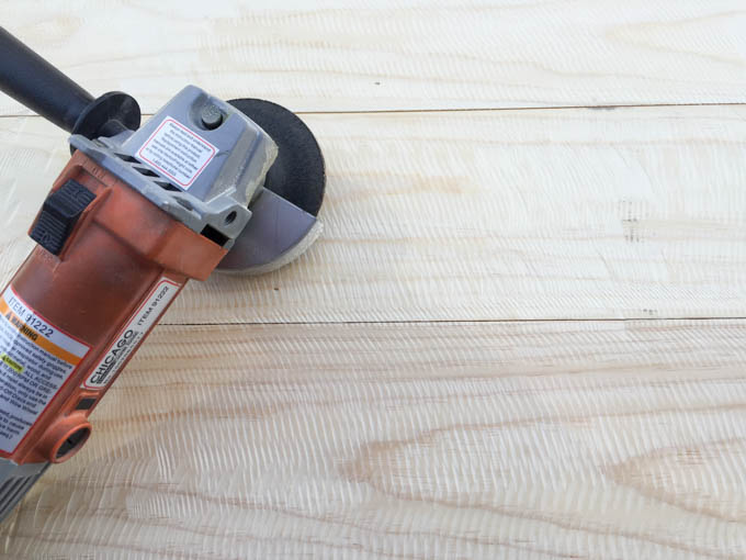 Angle grinder with sanding disc used to create a distressed sawmark texture on pine boards for the DIY rustic bed frame