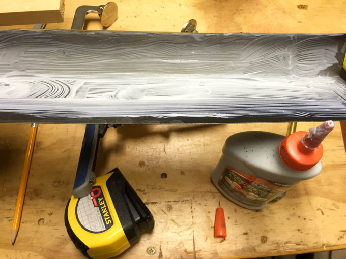 Elmer's ProBond adhesive brushed across the face of roof flashing before clamping the metal cap to the top of the DIY headboard