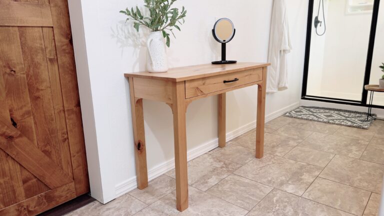 three quarter angle view of the makeup table in the bathroom with a robe hanging in the background