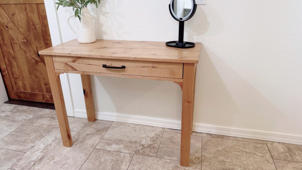 front view of the makeup table in full view with a makeup mirror and vase with greenery