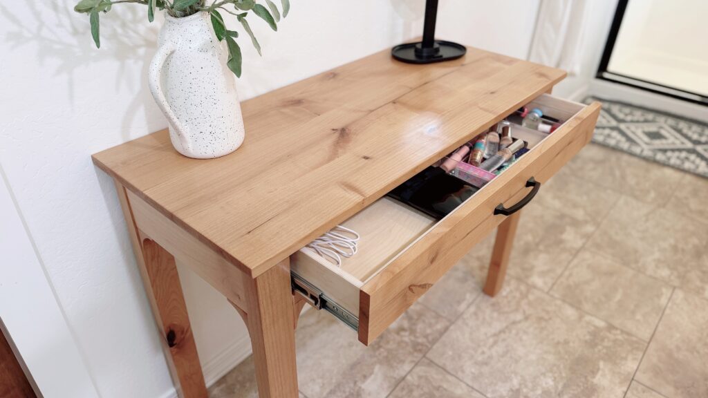 makeup table with the drawer open showing makeup and accessories inside