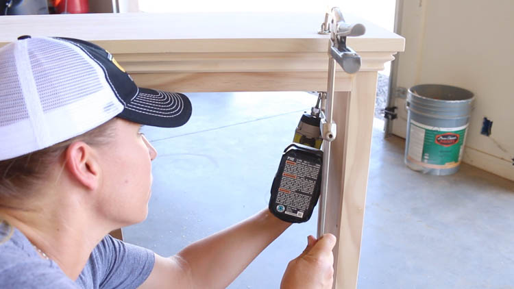 Applying wood glue along the cabinet frame before attaching the top