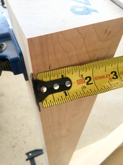 Measuring and marking a maple table leg with a Stanley tape measure to lay out the side rail position