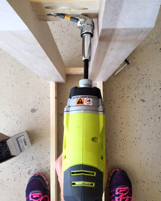 Using an impact driver with an off-set screwdriver adapter to drive a pocket screw into the narrow space between table legs