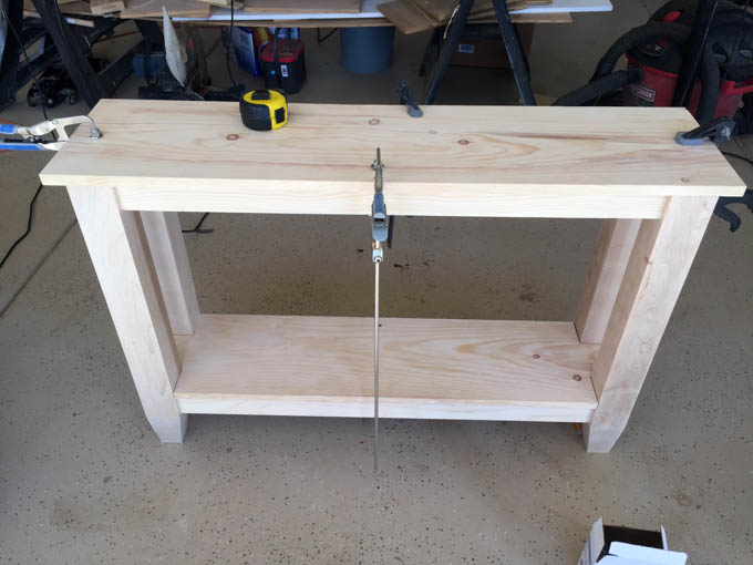 Fully assembled unfinished narrow console table with tapered legs and bottom shelf, sanded and ready for paint