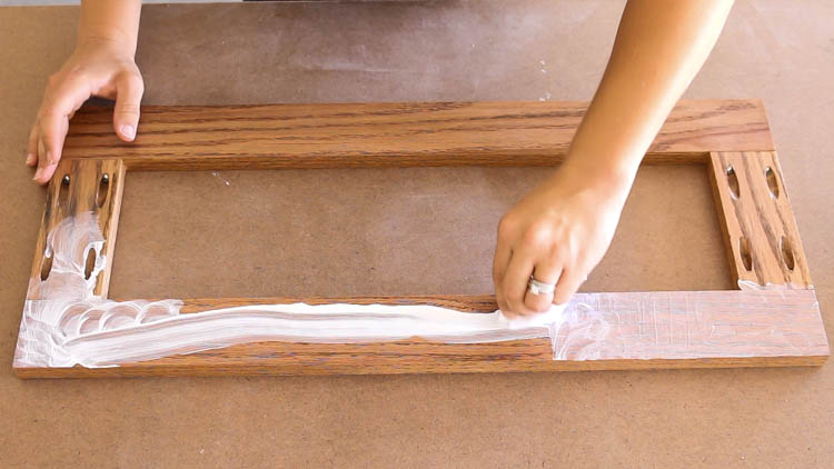 Rubbing white wax into the stained oak door frame for a weathered finish