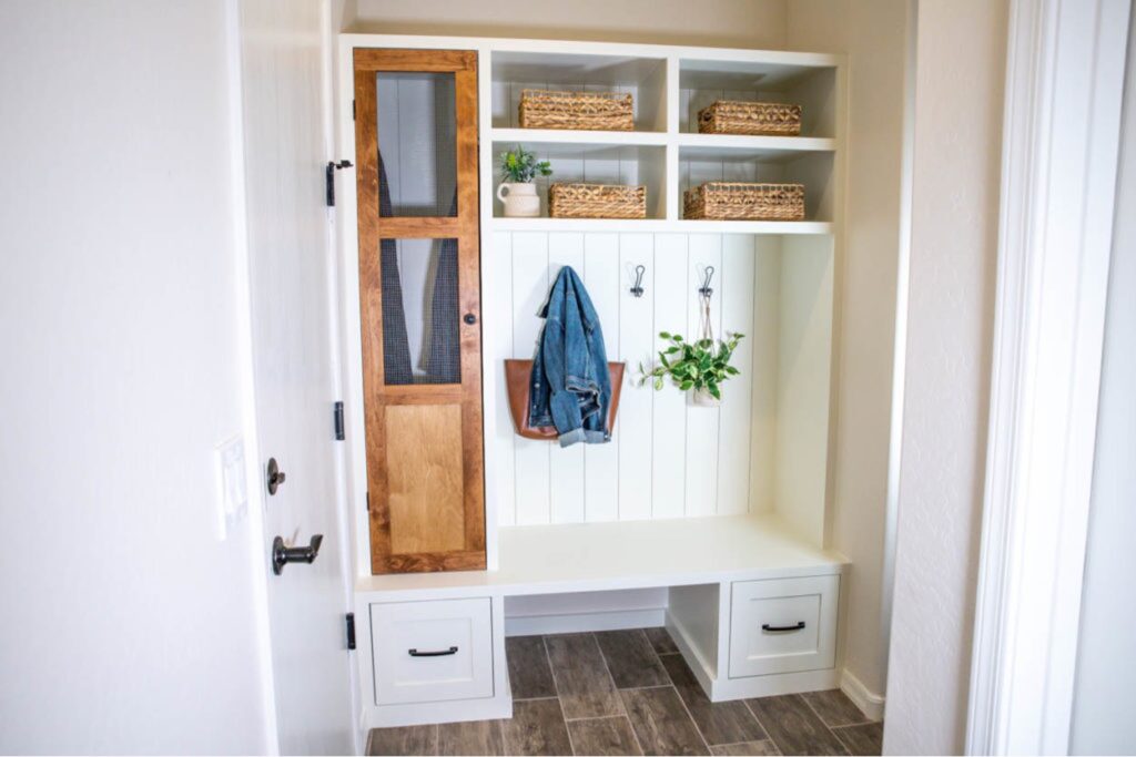 Finished DIY mudroom built-in with a bench, two drawers, open shelving, hooks and a tall wood cabinet