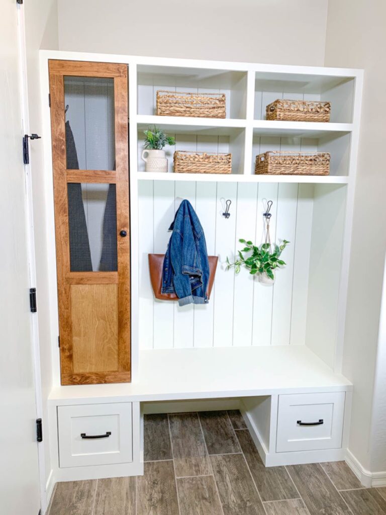 Finished custom mudroom built-in with bench, drawers, open cubbies, hooks and tall cabinet storage