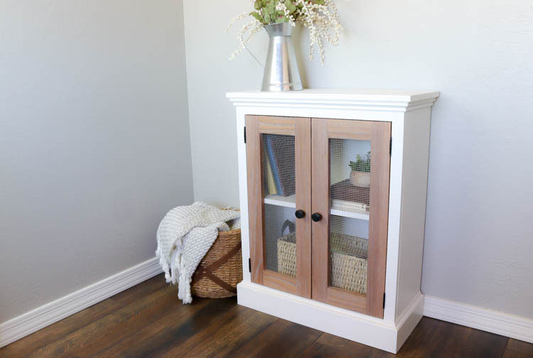 angled view of the two tone cabinet styled in a corner of a room