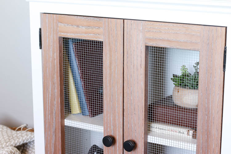 Close-up of the two-tone cabinet's oak mesh door and open shelf styled with books and a succulent