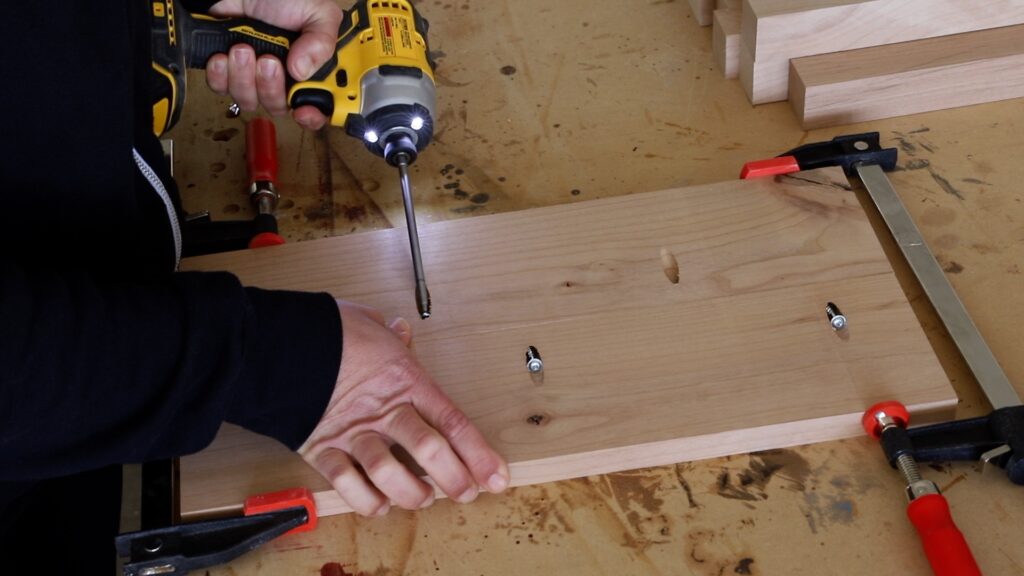 Driving pocket screws into a wood board to build the drawer front panel of a DIY side table