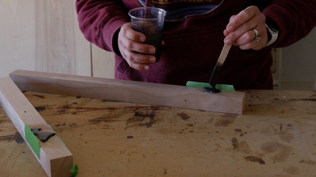 Applying gray-tinted epoxy to fill large knots in knotty alder lumber before building a side table
