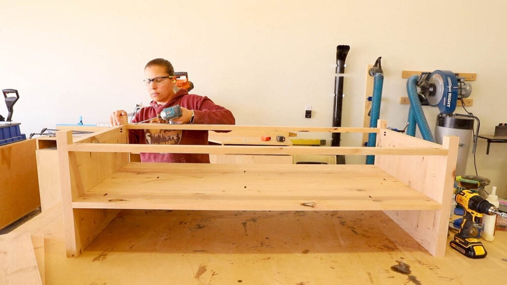 Coffee table base with lower shelf and 1x2 aprons being attached with an impact driver